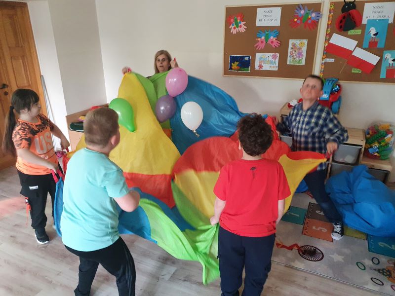 Uczniowie bawią się chustą i balonami